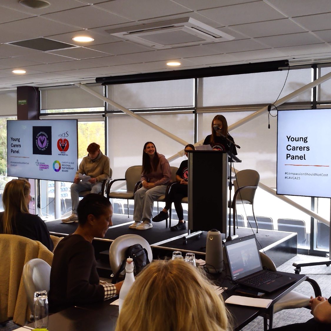 A panel discussion with speakers addressing an audience in a conference setting.